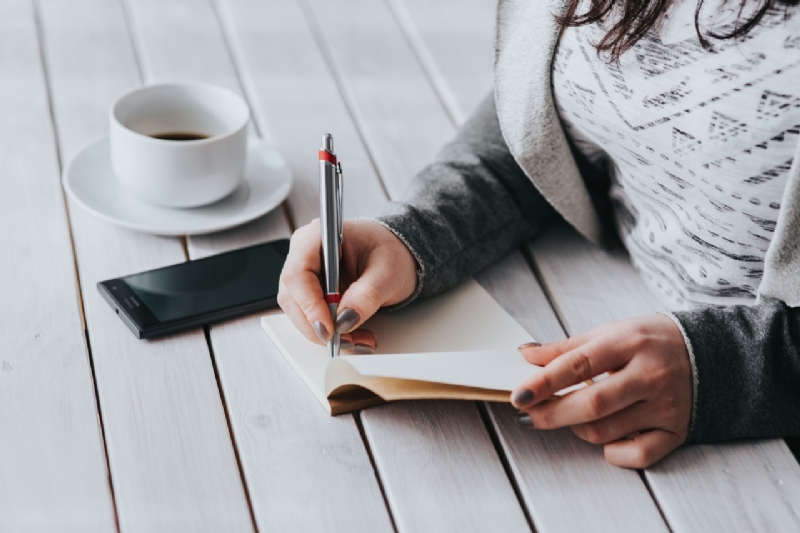 kaboompics_Coffee on table with a woman writing.jpg 方案配图,客户爱好,阅读,