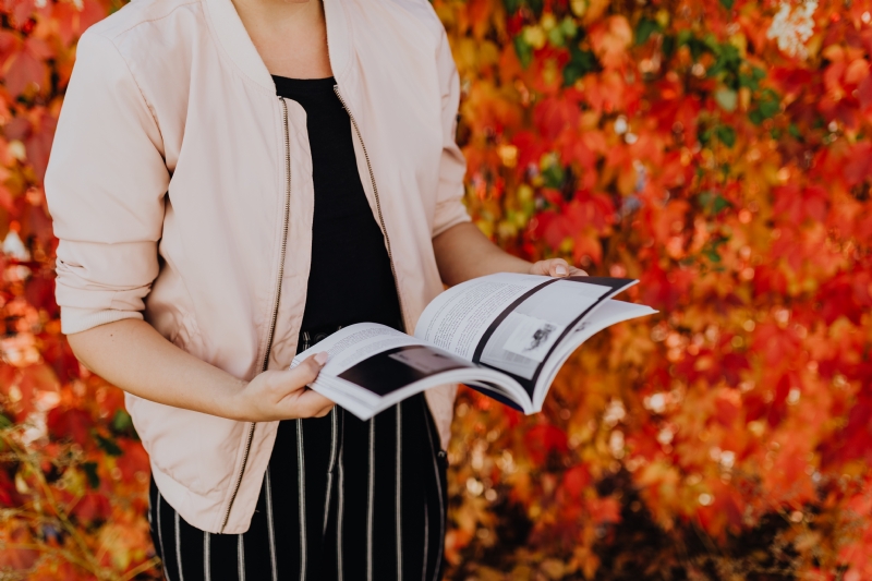 kaboompics_Girl with the Grafconf book on the background of coloured leaves.jpg 方案配图,客户爱好,阅读,