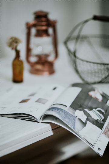 阅读 kaboompics_Magazine with a paraffin lamp on a white table.jpg