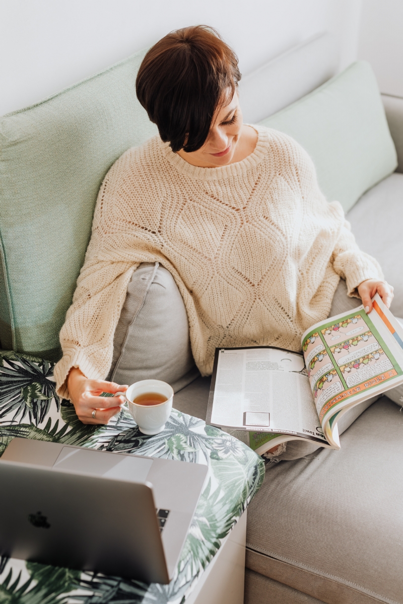 kaboompics_The woman is drinking tea on the couch, reading the newspaper and using a laptop.jpg 方案配图,客户爱好,阅读,