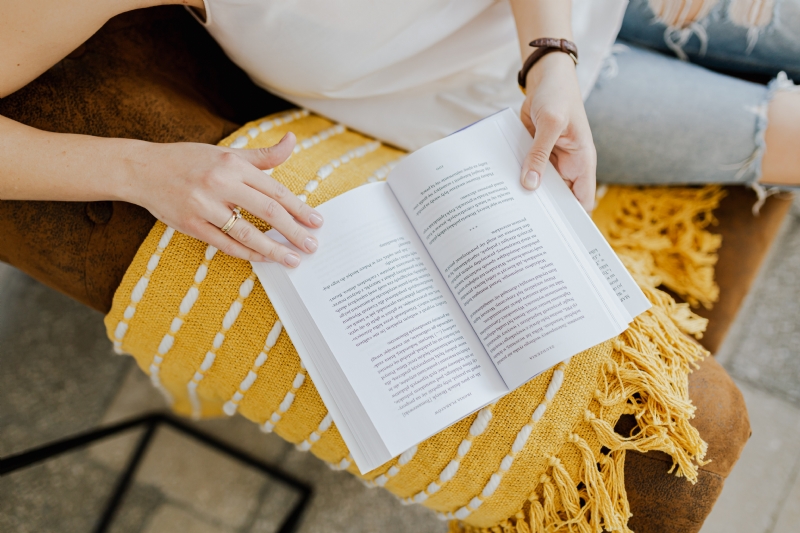 kaboompics_The woman is reading a book. She is sitting on a brown couch and a yellow blanket.jpg 方案配图,客户爱好,阅读,