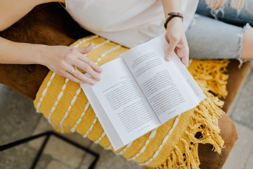 阅读 kaboompics_The woman is reading a book. She is sitting on a brown couch and a yellow blanket.jpg