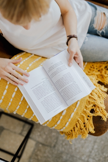 阅读 kaboompics_The woman is reading a book. She is sitting on a brown couch and a yellow blanket-2.jpg